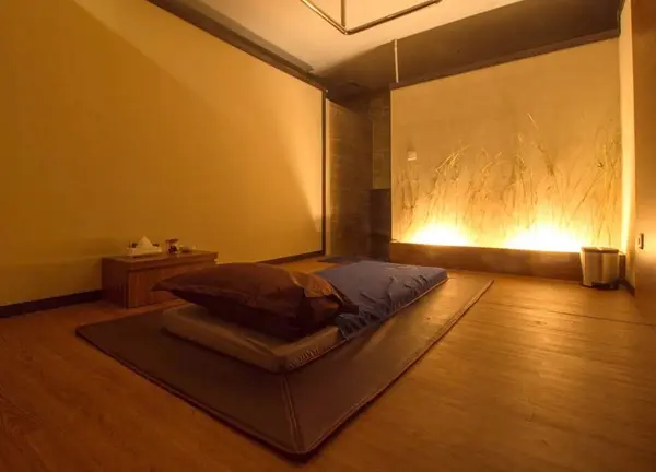 Cozy private massage room with floor mattress and warm lighting at Pudu Spa